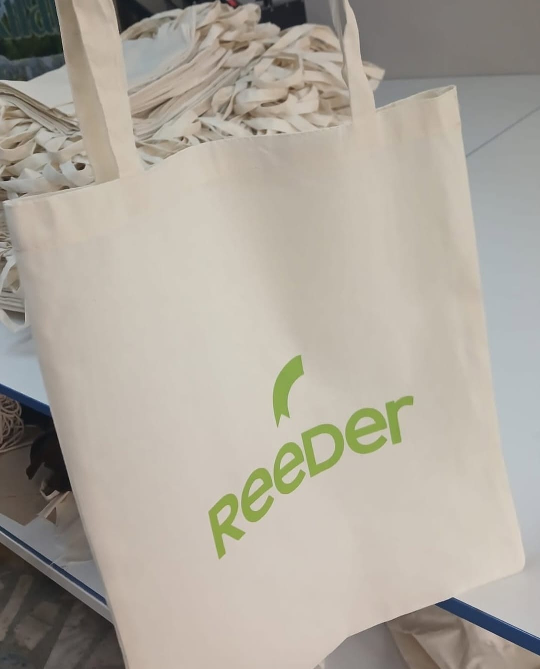 Reeder logosu yeşil renkte basılmış açık renkli kurumsal bez çanta